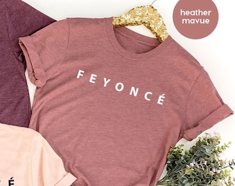 Può includere: Tre magliette con il testo "FEYONCÉ" in lettere bianche su una maglietta color malva heather, marrone heather e pesca heather.