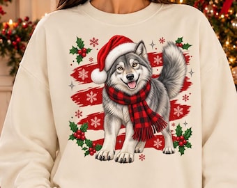 May include: A cream-coloured crewneck sweatshirt featuring a graphic of a grey husky dog wearing a red Santa hat and a red and black buffalo plaid scarf, surrounded by red holly berries, green leaves, and white snowflakes.