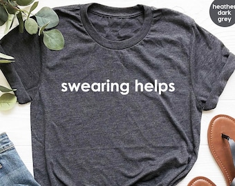 Peut inclure: T-shirt gris foncé chiné avec le texte "swearing helps" imprimé en blanc.