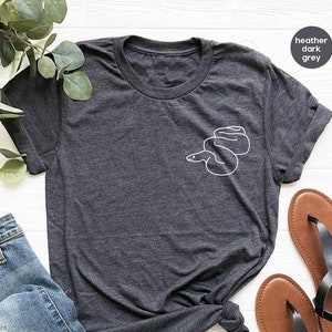 May include: A heather dark grey t-shirt with a white outline of a snake on the left side of the chest.