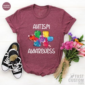 May include: Heather maroon t-shirt with a colorful puzzle piece graphic and the text "Autism Awareness".