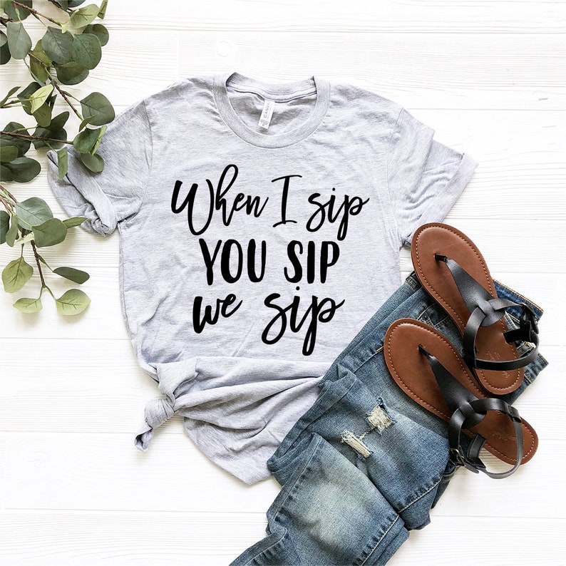 以下が含まれることがあります： 黒い文字で「When I sip you sip we sip」と書かれたグレーのTシャツ