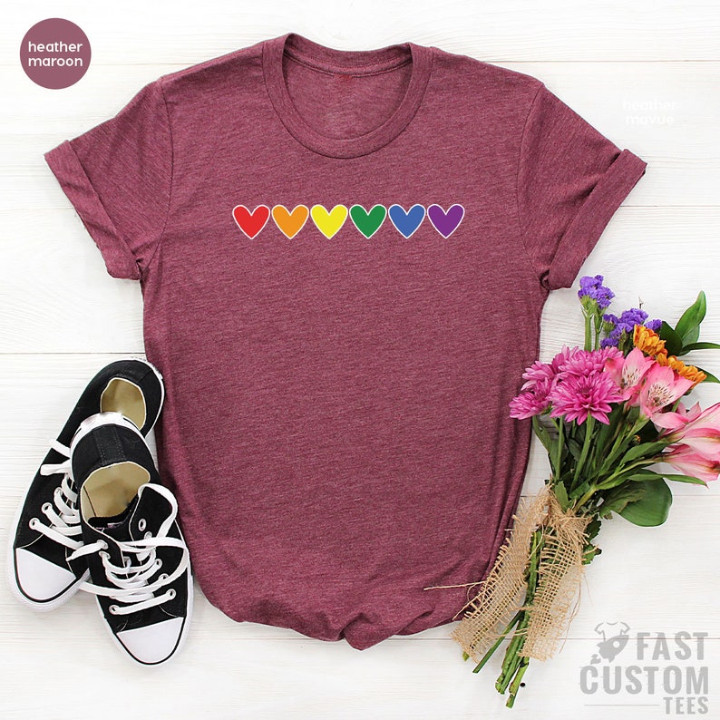 May include: A heather maroon t-shirt with a row of rainbow hearts printed on the front.