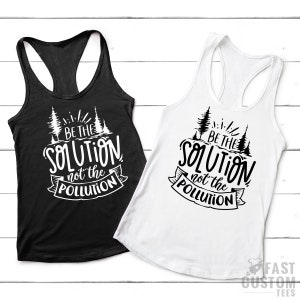 May include: Two tank tops with a black and white design. The design features a stylized tree with the text "BE THE SOLUTION not the POLLUTION".