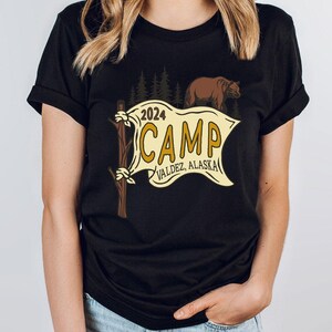 a woman wearing a black t - shirt that says camp