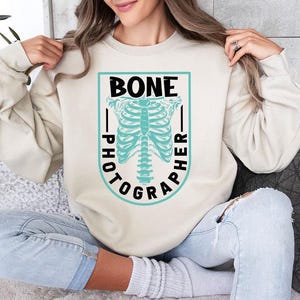 a woman sitting on a couch wearing a sweater with a skeleton on it