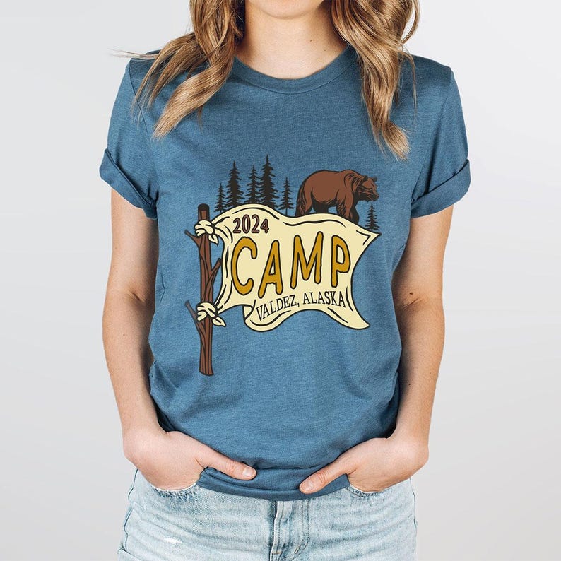 a woman wearing a t - shirt that says camp and a bear