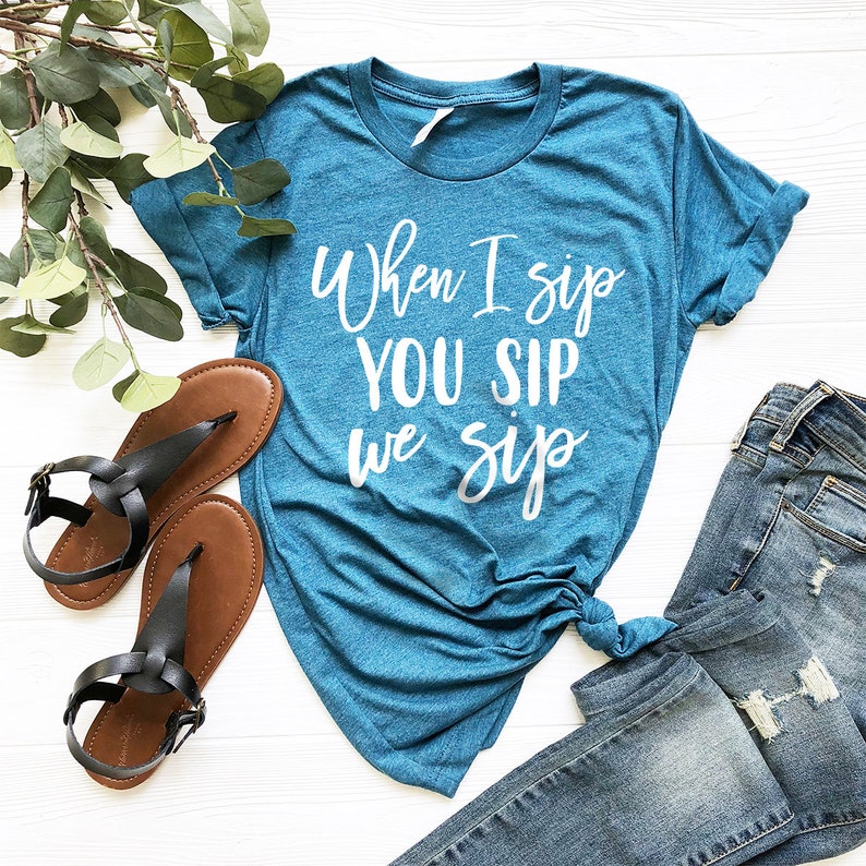 以下が含まれることがあります： 白い文字で「When I sip you sip we sip」と書かれたターコイズブルーのTシャツです。