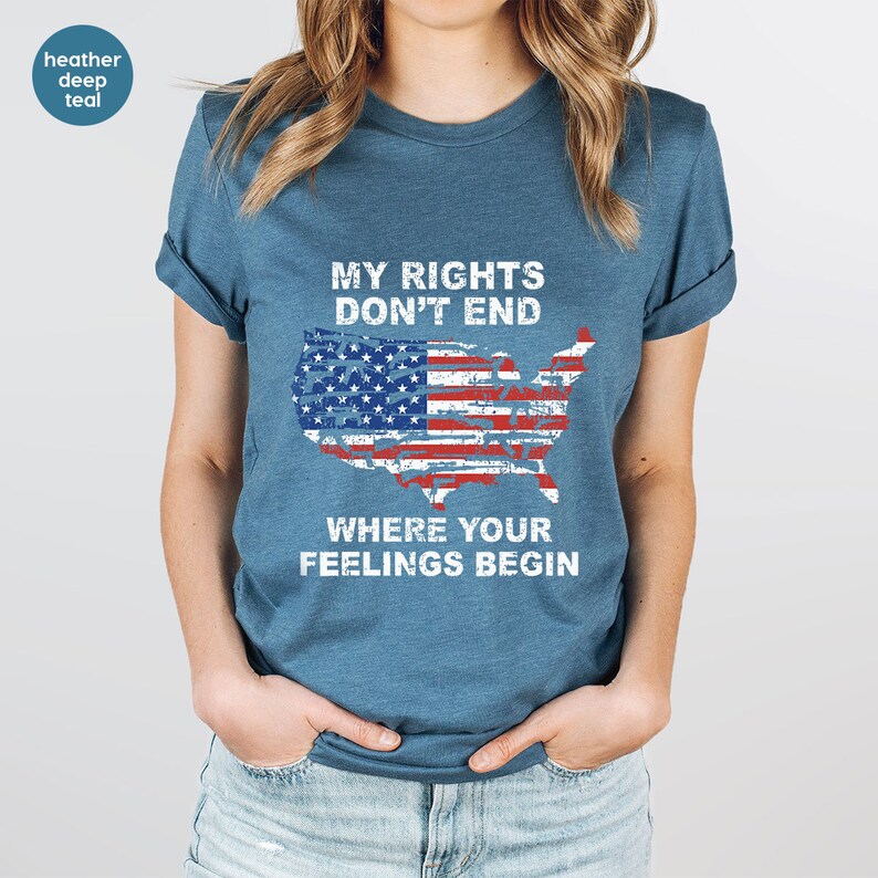May include: Teal t-shirt featuring the text "MY RIGHTS DON'T END WHERE YOUR FEELINGS BEGIN" and a graphic of the USA flag in the shape of the United States. The shirt has short sleeves and a crew neck.