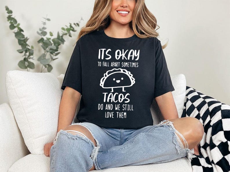 May include: A black t-shirt with white text that reads "It's okay to fall apart sometimes. Tacos do and we still love them." The shirt features a cartoon taco with a smiling face.