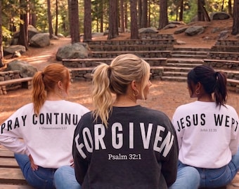 May include: Three people wearing sweatshirts with inspirational messages. The center person's sweatshirt is dark gray with the word "FORGIVEN" and "Psalm 32:1". The other two sweatshirts are white, one says "PRAY CONTINU" and "1 Thessalonians 5:17", the other says "JESUS WEPT" and "John 11:35".