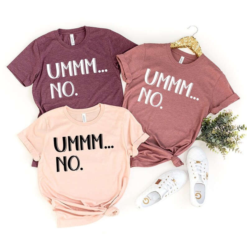 May include: Three t-shirts with the text "UMMM... NO." printed on them. The shirts are in different colors: maroon, pink, and a lighter shade of maroon.