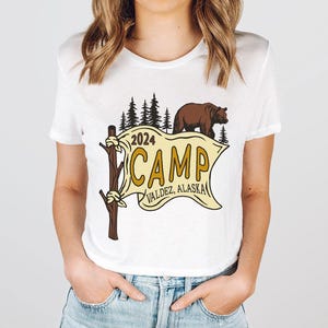 a woman wearing a white t - shirt with a brown bear on it
