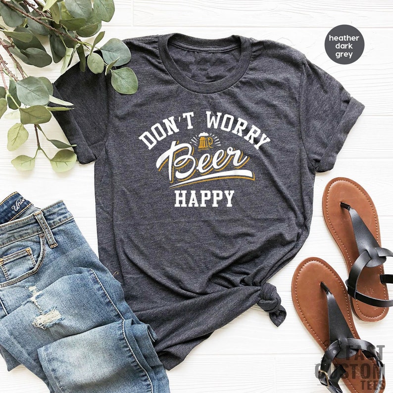 May include: A heather dark grey t-shirt with the text "Don't Worry Beer Happy" in white lettering. A small beer mug icon is above the word "Beer".