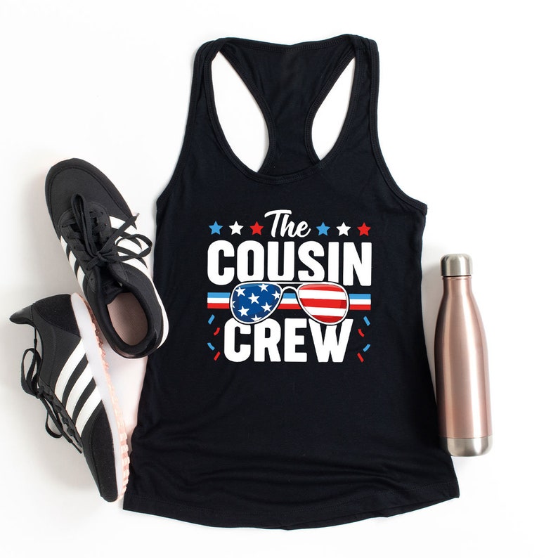 May include: Black tank top with the text "The Cousin Crew" in white with red, white, and blue sunglasses graphic. The sunglasses have stars on the lenses and a red, white, and blue striped band.