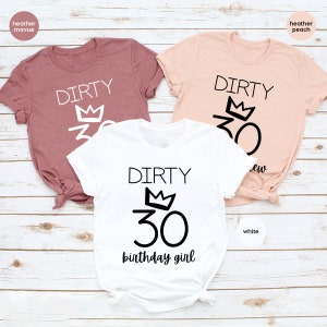 May include: Three t-shirts with the text "Dirty 30" and a crown above the number. The shirts are in heather mauve, heather peach, and white. The white shirt also has the text "birthday girl" below the number.
