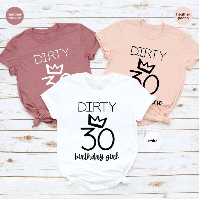 May include: Three t-shirts with the text "Dirty 30" and a crown above the number. The shirts are in heather mauve, heather peach, and white. The white shirt also has the text "birthday girl" below the number.