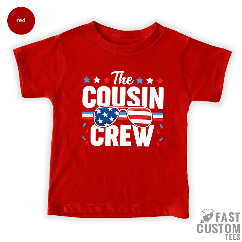 May include: Red t-shirt with a white graphic that says "The Cousin Crew" with an American flag design in sunglasses.