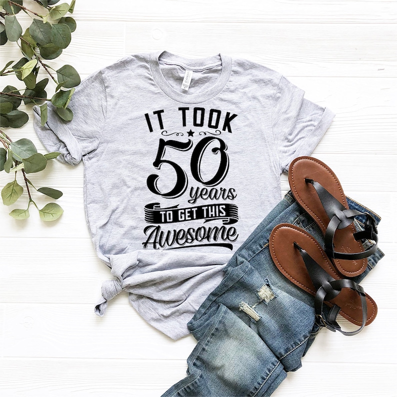 May include: Gray t-shirt with black text that reads "It took 50 years to get this awesome".