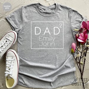 May include: Heather grey t-shirt with a white square design that says "DAD^2 Emily John"