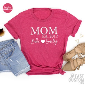 May include: Heather raspberry t-shirt with white text that reads "MOM Est. 2012 Luke Emily" with a heart between the names.