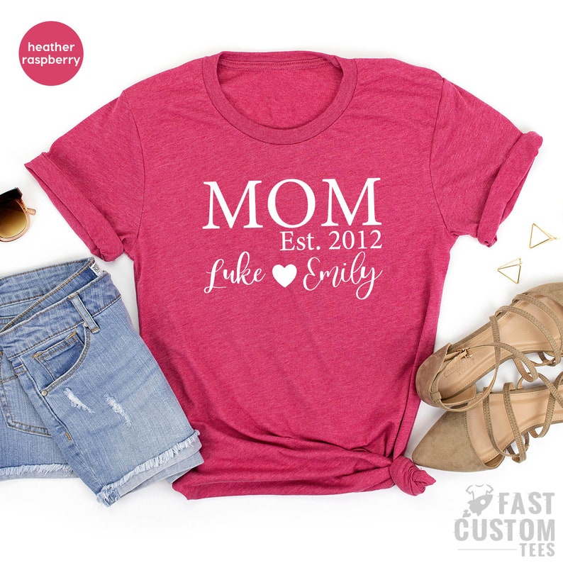 May include: Heather raspberry t-shirt with white text that reads "MOM Est. 2012 Luke Emily" with a heart between the names.