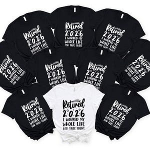 A collection of black t-shirts with white text that reads "Retired 2026 I worked my whole life for this shirt" arranged in a circular pattern.