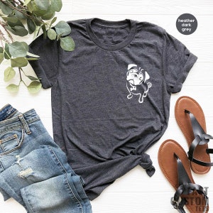 May include: A heather dark grey t-shirt featuring a white graphic of a pug wearing a bow tie. The shirt is laid flat on a white surface with a pair of brown sandals and blue jeans.