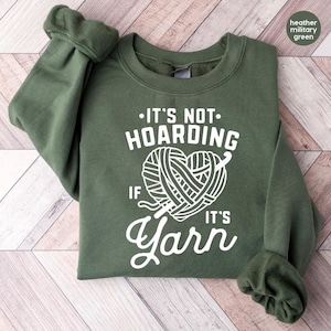 a green sweater with a ball of yarn on it