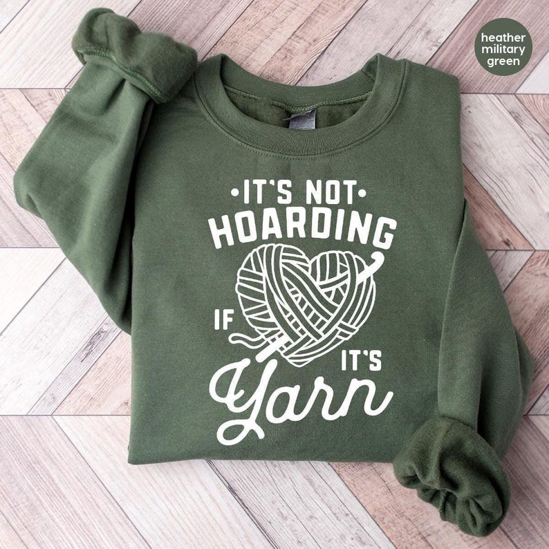 a green sweater with a ball of yarn on it
