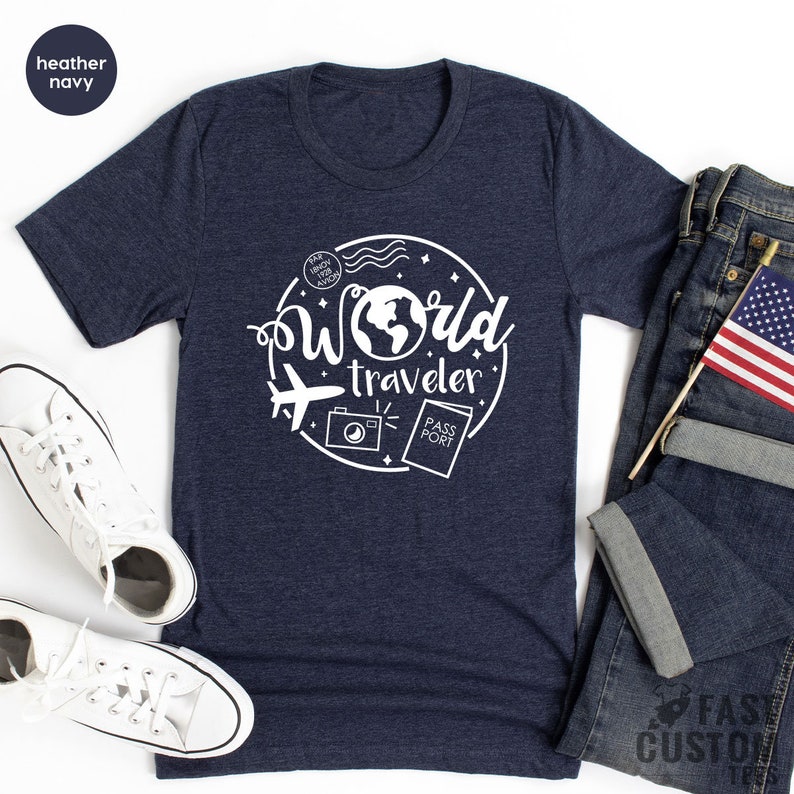 May include: A heather navy blue t-shirt with a white graphic design of a world with the text "World Traveler" and travel icons.