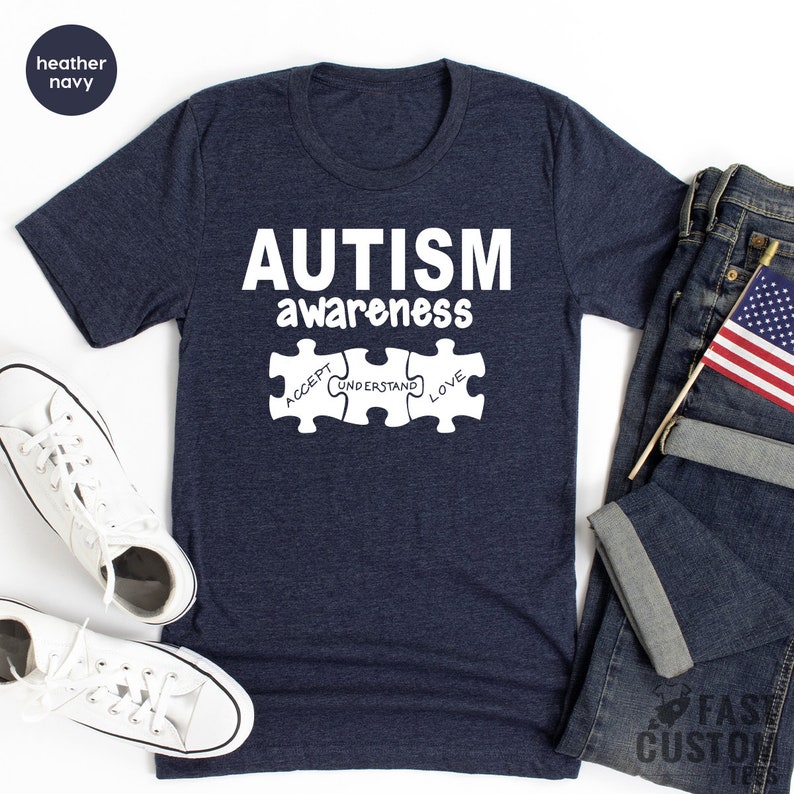 May include: A navy blue t-shirt with the text "AUTISM awareness" and three puzzle pieces with the words "ACCEPT", "UNDERSTAND", and "LOVE" on them.