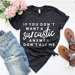 May include: Black t-shirt with white text that reads "If you don't want a sarcastic answer don't ask me".