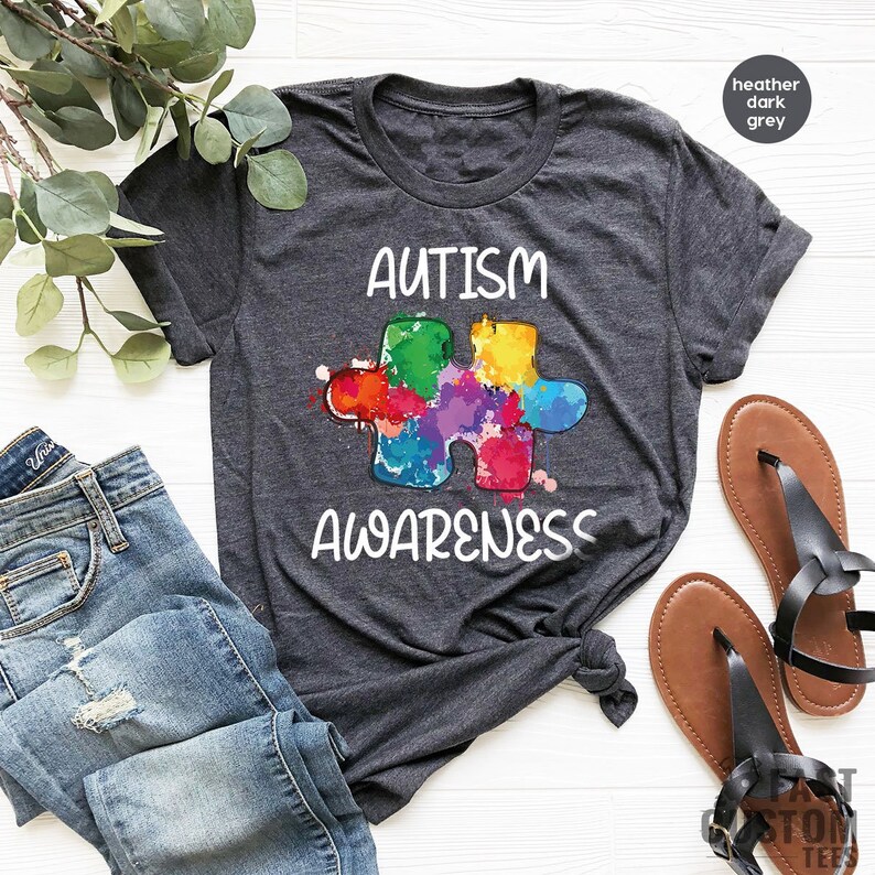 May include: Heather dark grey t-shirt with a colorful puzzle piece and the text "Autism Awareness".