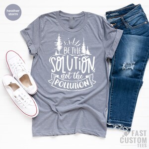 May include: Heather grey t-shirt with a white graphic that says "Be the Solution not the Pollution" with a stylized tree design.
