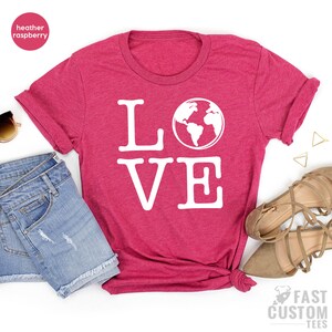 May include: A heather raspberry t-shirt with the word "LOVE" in white text with a white outline. The "O" in LOVE is replaced with a white outline of the Earth.