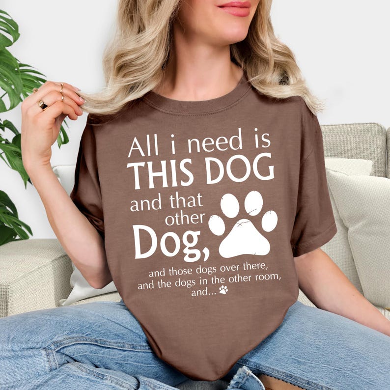 A woman wearing a brown t-shirt with a humorous text printed on it, sitting on a couch.