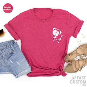 May include: A heather raspberry t-shirt with a white pug graphic on the front. The shirt is made of a soft, comfortable material and is perfect for everyday wear.