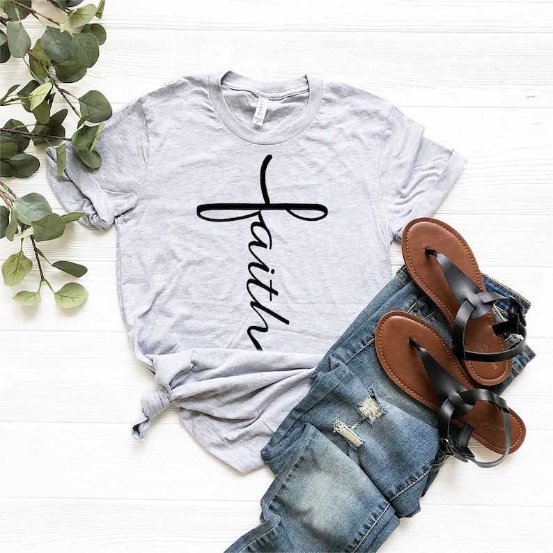 May include: A gray t-shirt with a black cross and the word "faith" written vertically down the cross.