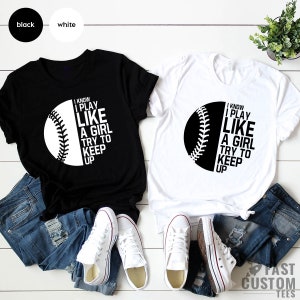 Op de afbeelding: Twee T-shirts met een baseball-afbeelding en de tekst "I know I play like a girl try to keep up". Een T-shirt is zwart met witte tekst en de andere is wit met zwarte tekst.