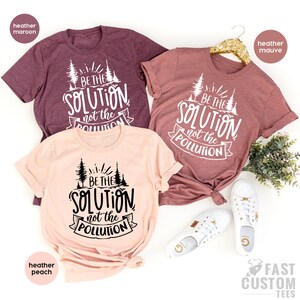 May include: Three t-shirts with the text "Be the solution, not the pollution" in black and white. The shirts are in heather maroon, heather peach, and heather mauve.