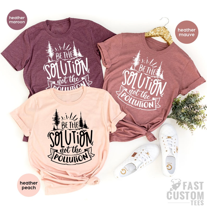 May include: Three t-shirts with the text "Be the solution, not the pollution" in black and white. The shirts are in heather maroon, heather peach, and heather mauve.