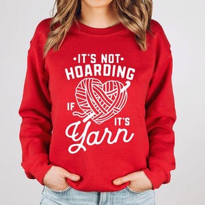 a woman wearing a red sweater that says it's not hoarding if it