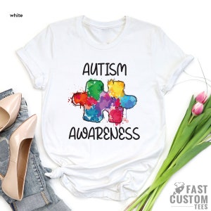 May include: White t-shirt with a colorful puzzle piece design and the text "Autism Awareness".