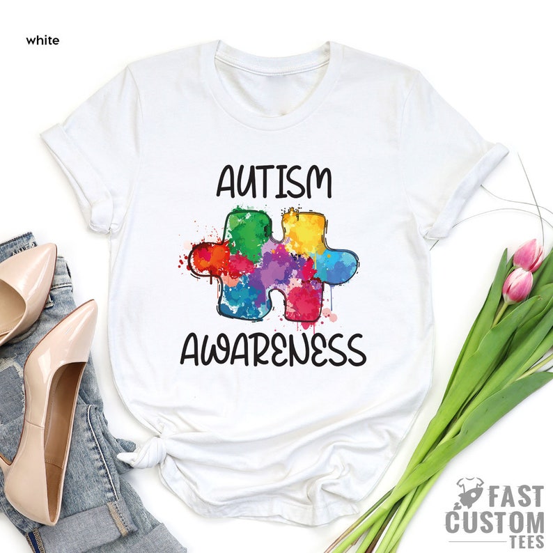 May include: White t-shirt with a colorful puzzle piece design and the text "Autism Awareness".