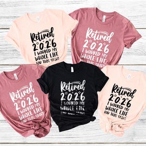 a collection of five t-shirts with the same text printed on them, arranged on a wooden background.