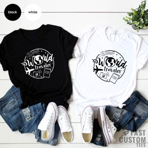 May include: Two t-shirts, one black and one white, with a graphic design of a globe, airplane, camera, and passport with the text "World Traveler".