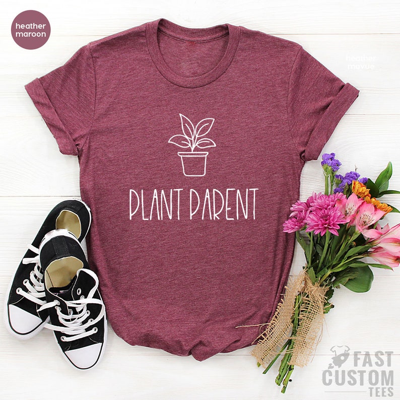 May include: A heather maroon t-shirt with a white outline of a potted plant and the text "Plant Parent".