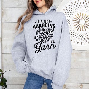 a woman wearing a gray hoodie that says it's not hoarding if