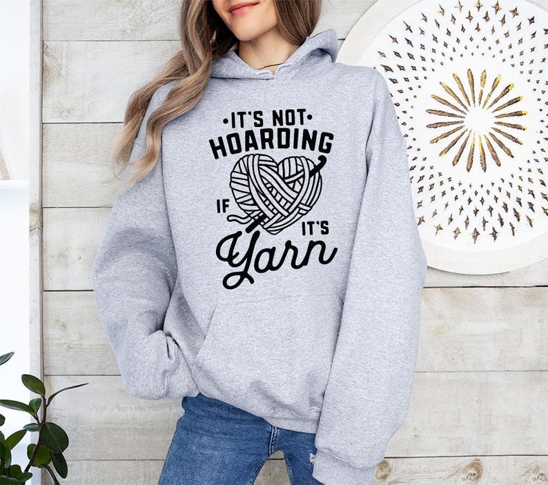 a woman wearing a gray hoodie that says it's not hoarding if